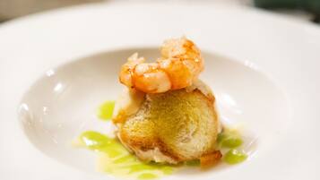 A shrimp on a piece of bread with a green sauce.
