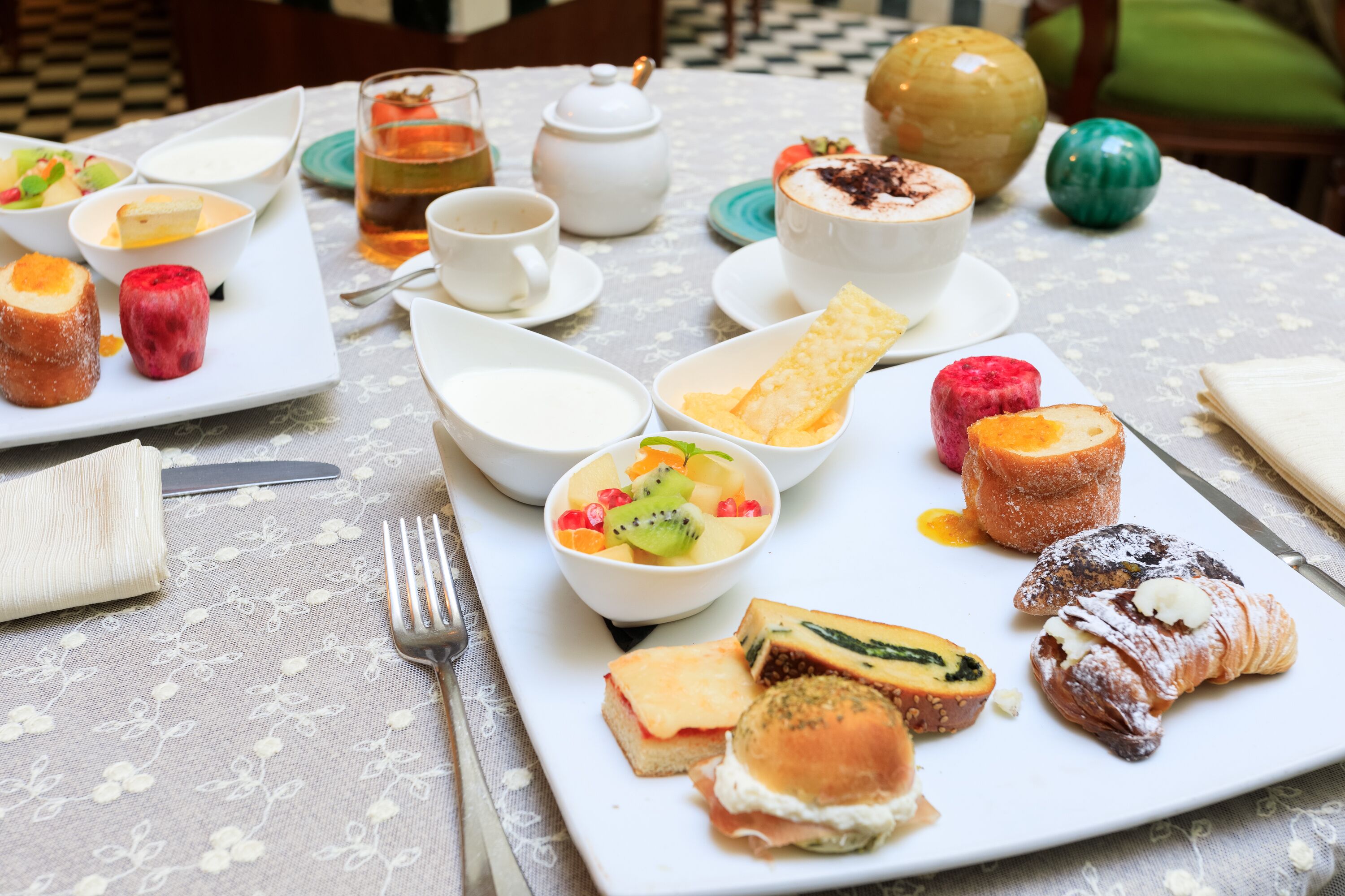 A table set with various food items including pastries, fruits, and a teapot.