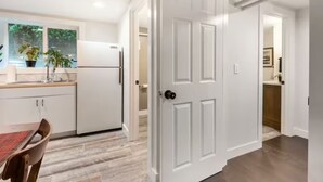 A modern kitchen with white cabinetry, a dining table, and a view of the outdoors. - A pied-à-terre near bistros, shops, and sports stadium w/ parking and EV charger (Portland)