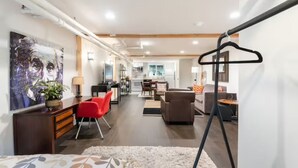 A modern living room with a sofa, red chairs, a coffee table, and a painting on the wall. - A pied-à-terre near bistros, shops, and sports stadium w/ parking and EV charger (Portland)