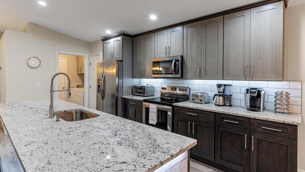 A modern kitchen with dark cabinets, stainless steel appliances, and a granite countertop.