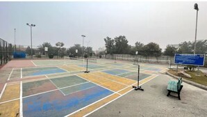 Un court de tennis extérieur comprenant plusieurs terrains, un banc et un panneau d’affichage.