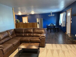 Relax in this inviting living space with a comfortable sofa, dining table, and chandelier.