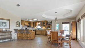 A spacious kitchen with wooden cabinets, a central island, and a dining area with wooden chairs. - Perfect getaway for all!  Fish and hunt with all the comforts of home! (Port Mansfield)