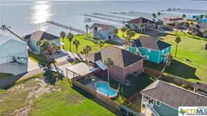 A coastal residential area with houses, a swimming pool, and a pier extending into the water. - Perfect getaway for all!  Fish and hunt with all the comforts of home! (Port Mansfield)