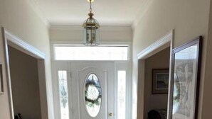 A hallway with a wooden floor, a white door with a glass panel, and a hanging light fixture. - The Berg Life:  Relax, Fish & Explore the Crystal Co (Marshallberg)