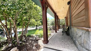 Un porche cubierto con escalones de piedra, columnas de madera y un banco.