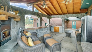 Una chimenea de piedra, muebles de mimbre y una pared de piedra.
