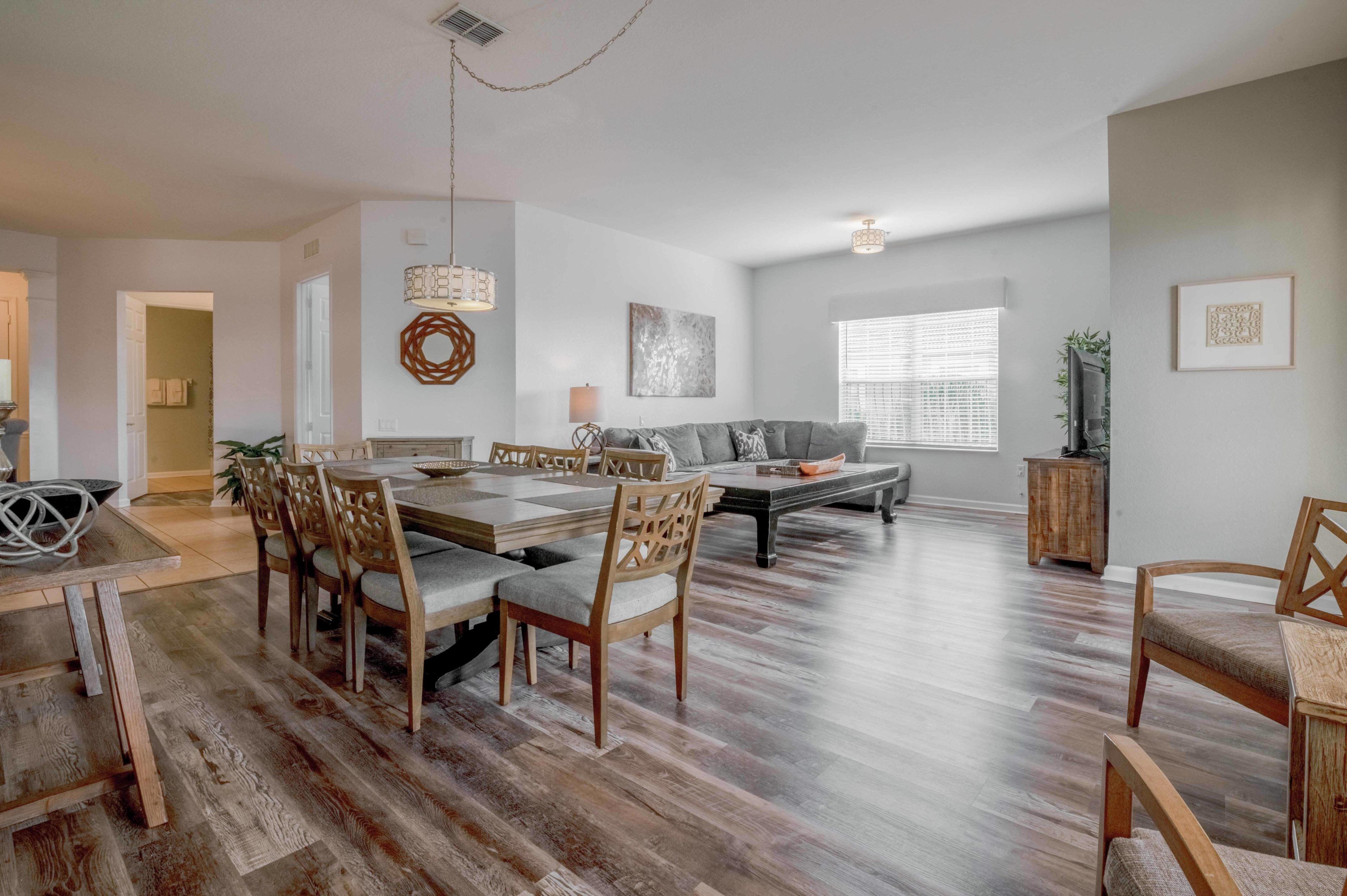 A spacious living area with a dining table, chairs, a sofa, and a coffee table.