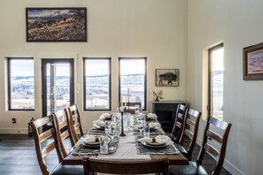 Una sala da pranzo con un grande tavolo apparecchiato per sei persone, ampie finestre che si affacciano su un paesaggio innevato e un quadro di un bisonte appeso al muro.