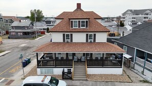 A two-story house with a porch, a garage, and a driveway. - Hampton Beach ♡ Ocean Retreat - Steps From The Sand and Strip! (Hampton)