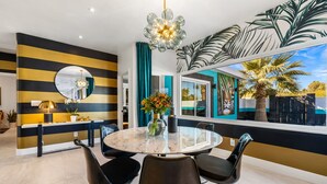 A modern dining area with a round table, black chairs, and a decorative mirror.
