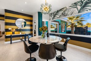 A modern dining area with a round table, black chairs, and a decorative mirror.
