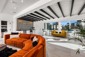 A modern living room with a large sectional sofa, a yellow armchair, and a dining area with a table and chairs. - Luxury Palm Springs Estate Pool, Spa & Mini-Golf (Palm Springs)