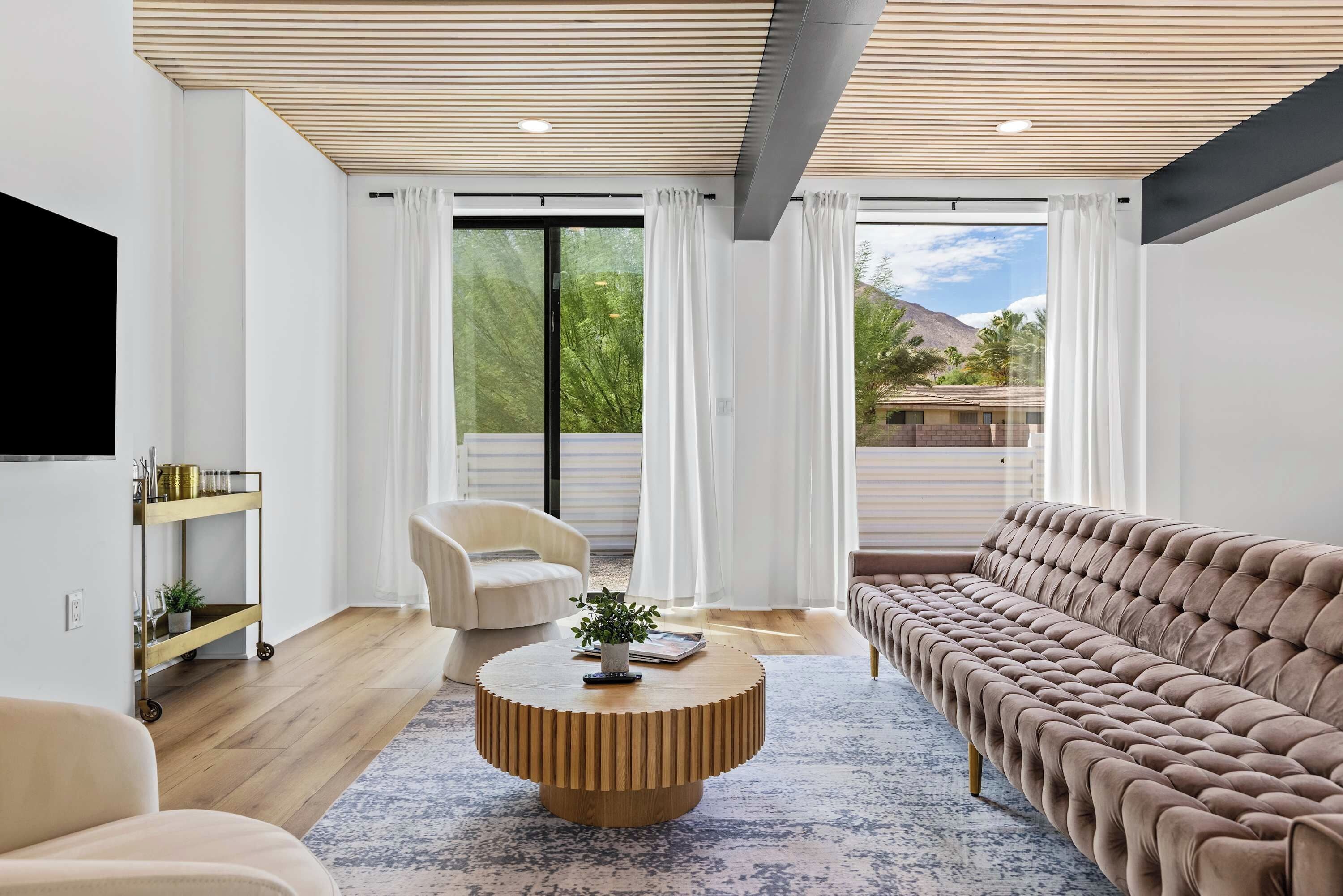 A modern living room with a sofa, a chair, a coffee table, and a TV mounted on the wall.