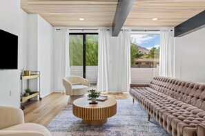 A modern living room with a sofa, a chair, a coffee table, and a TV mounted on the wall.