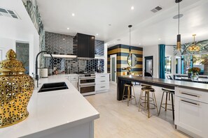 A modern kitchen with a central island, a built-in oven, and a large window.