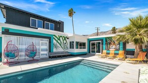 A modern house with a swimming pool, outdoor seating, and a mural.