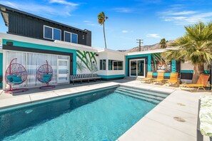 A modern house with a swimming pool, outdoor seating, and a mural.