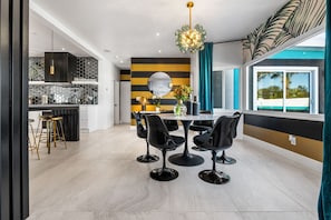 A modern kitchen with a striped backsplash, a dining area with black chairs, and a large window with a view.