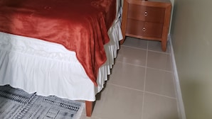 A bedroom with a bed, a nightstand, a lamp, and a ceiling fan.