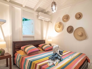 Un dormitorio con edredón a rayas, cabecera de madera y ventana con vistas.
