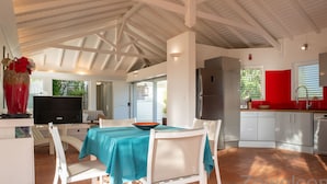A spacious kitchen with white cabinetry, a stainless steel refrigerator, and a dining area with a table set for four. - Villa Douceur Caraïbes, 500m from the beach, pool under the palm trees (Saint-Francois)