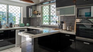Een moderne keuken met een centraal eiland, zwart-wit keukenkastjes en een uitzicht door grote ramen.