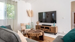 Een moderne woonkamer met een grote flatscreen televisie, een houten salontafel en een bank.