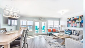 A modern living room with a dining area, a sofa set, a coffee table, and a TV mounted on the wall. - ⭐Gorgeous Beachhouse on Sand~Beach SVC~4 Gulf Front Masters~10BR Crystal Views (Destin)