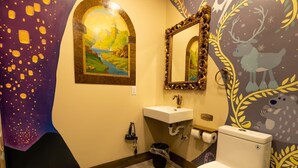 A bathroom with a painting, a sink, a mirror, and a toilet. - Storybook Cottage @ Four Fillies Lodge-Glamping (Peterstown)