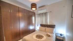 A bedroom with a large wardrobe, a bed with a headboard, a bedside table, and a nightstand. - Large and modern 2bedroom with balcony GLUB1-1 (Gzira)