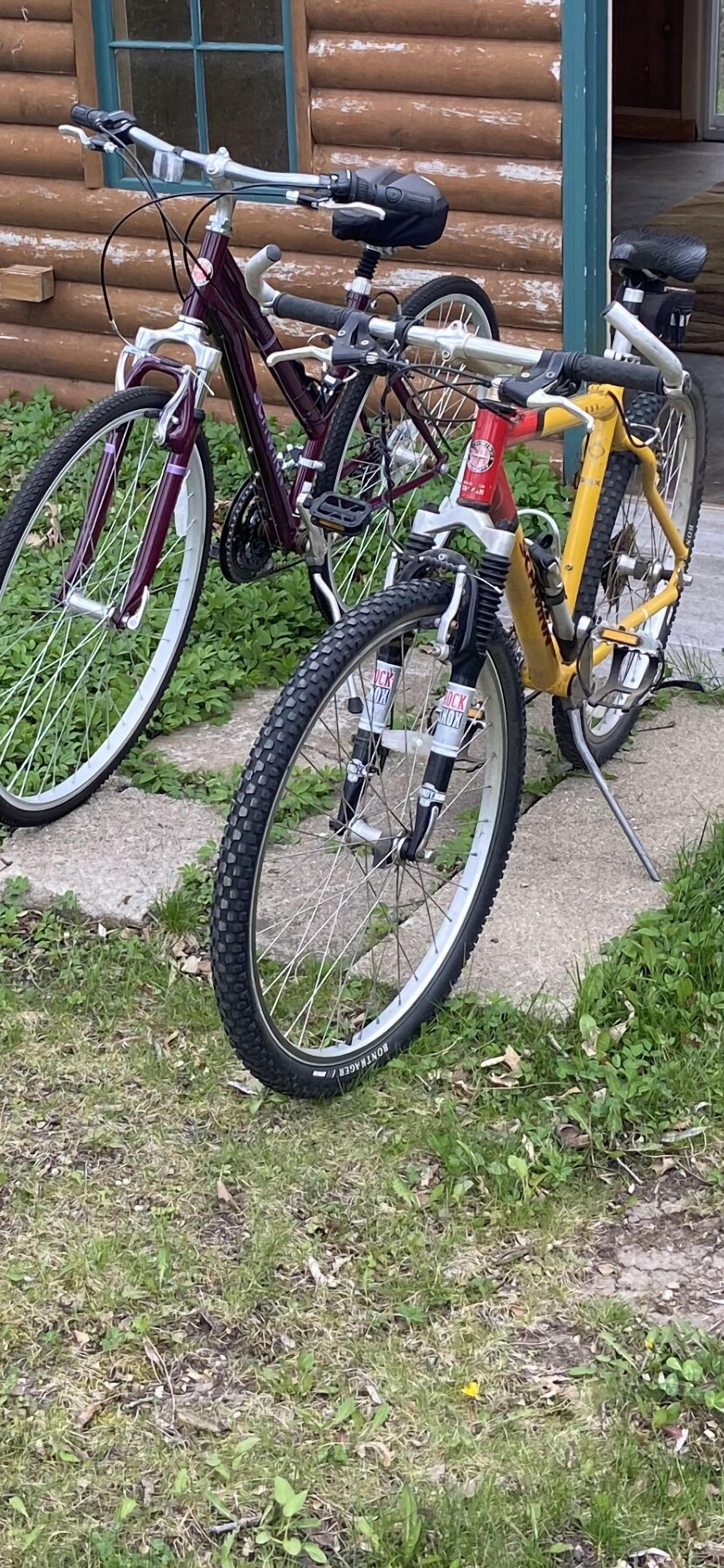 Two bicycles parked in front of a log cabin.