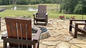 Une terrasse avec deux fauteuils Adirondack en bois et un foyer en pierre.