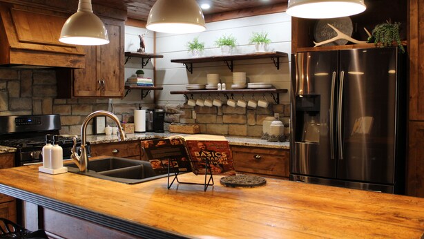 Une cuisine dotée d’un plan de travail en bois, d’appareils électroménagers en acier inoxydable et de luminaires suspendus.