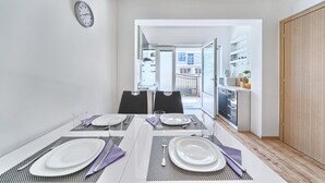 A modern dining area with a table set for four, a kitchen visible through an open door, and a clock on the wall. - Apartment in Kaštel Lukšić with Terrace, Air condition, WIFI, Washing machine (5107-2) (Kaštel Lukšic)
