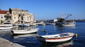 A harbor with several boats docked, a building with a red roof, and a clear blue sky. - Apartment in Kaštel Lukšić with Terrace, Air condition, WIFI, Washing machine (5107-2) (Kaštel Lukšic)