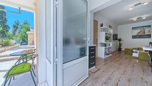 A modern living room with a sliding glass door leading to an outdoor area, a white shelving unit, and a painting on the wall. - Apartment in Kaštel Lukšić with Terrace, Air condition, WIFI, Washing machine (5107-2) (Kaštel Lukšic)