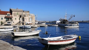 A harbor with several boats docked, a building with a red roof, and a clear blue sky.