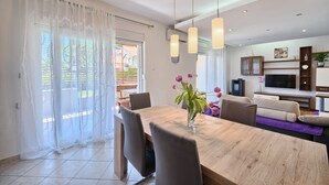 A modern living room with a wooden dining table, chairs, a sofa, a TV, and a plant. - Apartment in Kaštel Lukšić with Terrace, Air condition, WIFI, Washing machine (5107-3) (Kaštel Lukšic)