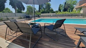 An outdoor pool area with a wooden deck, two lounge chairs, and a table with an umbrella. - Apartment in Kaštel Lukšić with Terrace, Air condition, WIFI, Washing machine (5107-3) (Kaštel Lukšic)