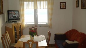 A room with a dining table, chairs, a TV, a sofa, and a window with curtains. - Apartment in Dugi Rat with Seaview, Terrace, Air condition, WIFI (5112-1) (Dugi Rat)