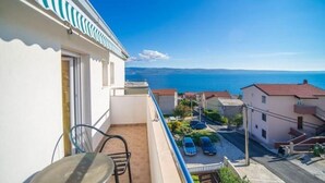 A balcony with a view of the sea, a table, and chairs.