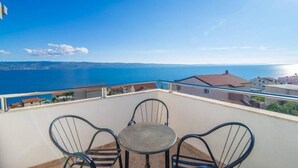 Un balcon avec une table et des chaises donnant sur une vue panoramique de la côte.