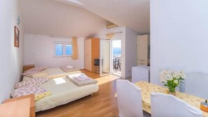 Une chambre avec deux lits, une table à manger et une vue sur la mer.