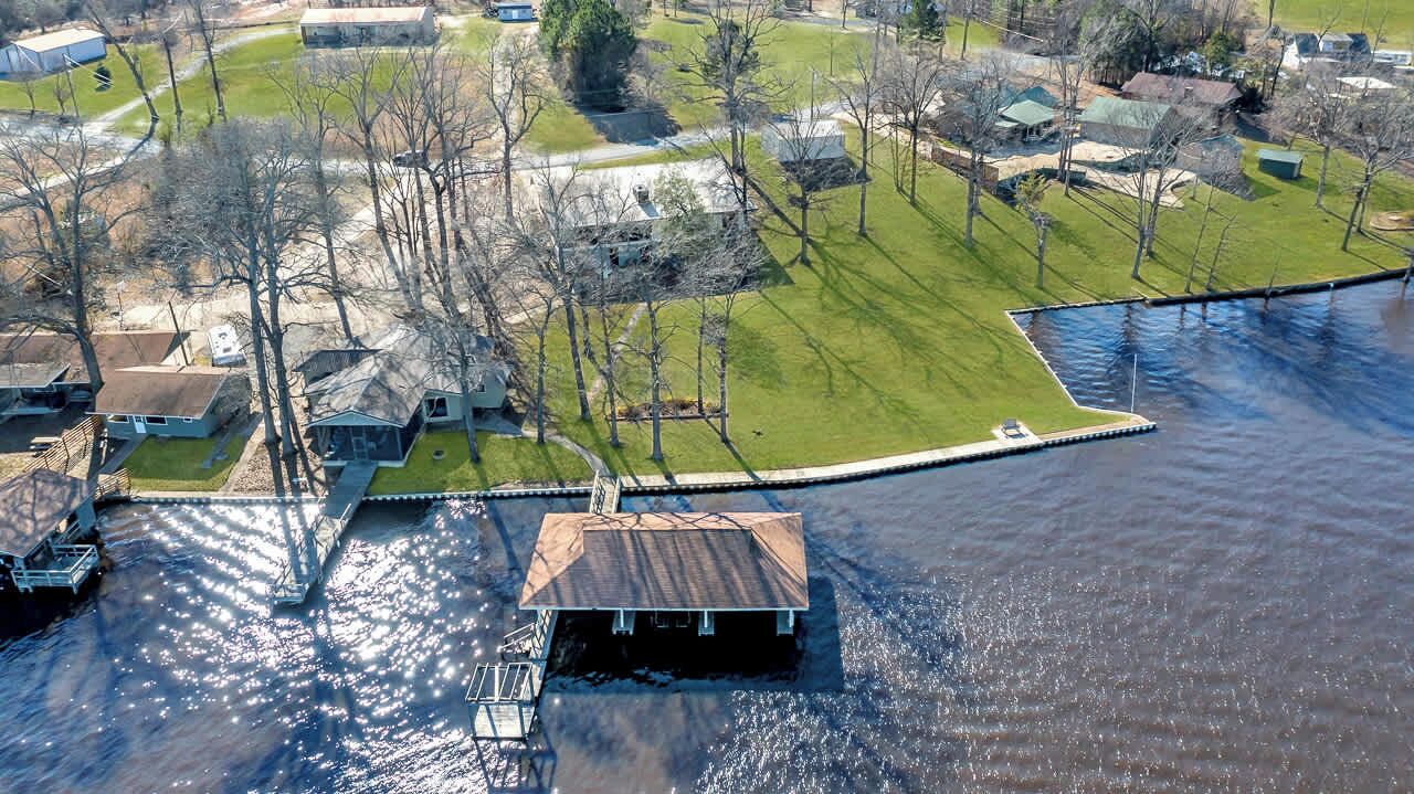 Vista aérea de uma área residencial com casas, um cais e um barco pequeno.