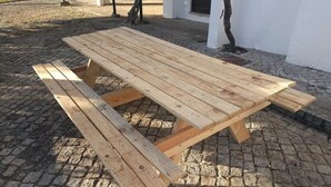 A wooden picnic table with benches on a cobblestone surface.