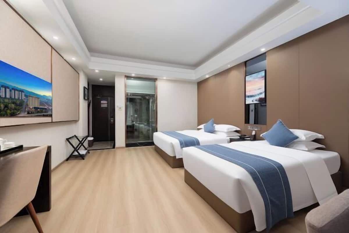 Ein Hotelzimmer mit zwei Betten, einem Schreibtisch, einem Stuhl und einem Fernseher.