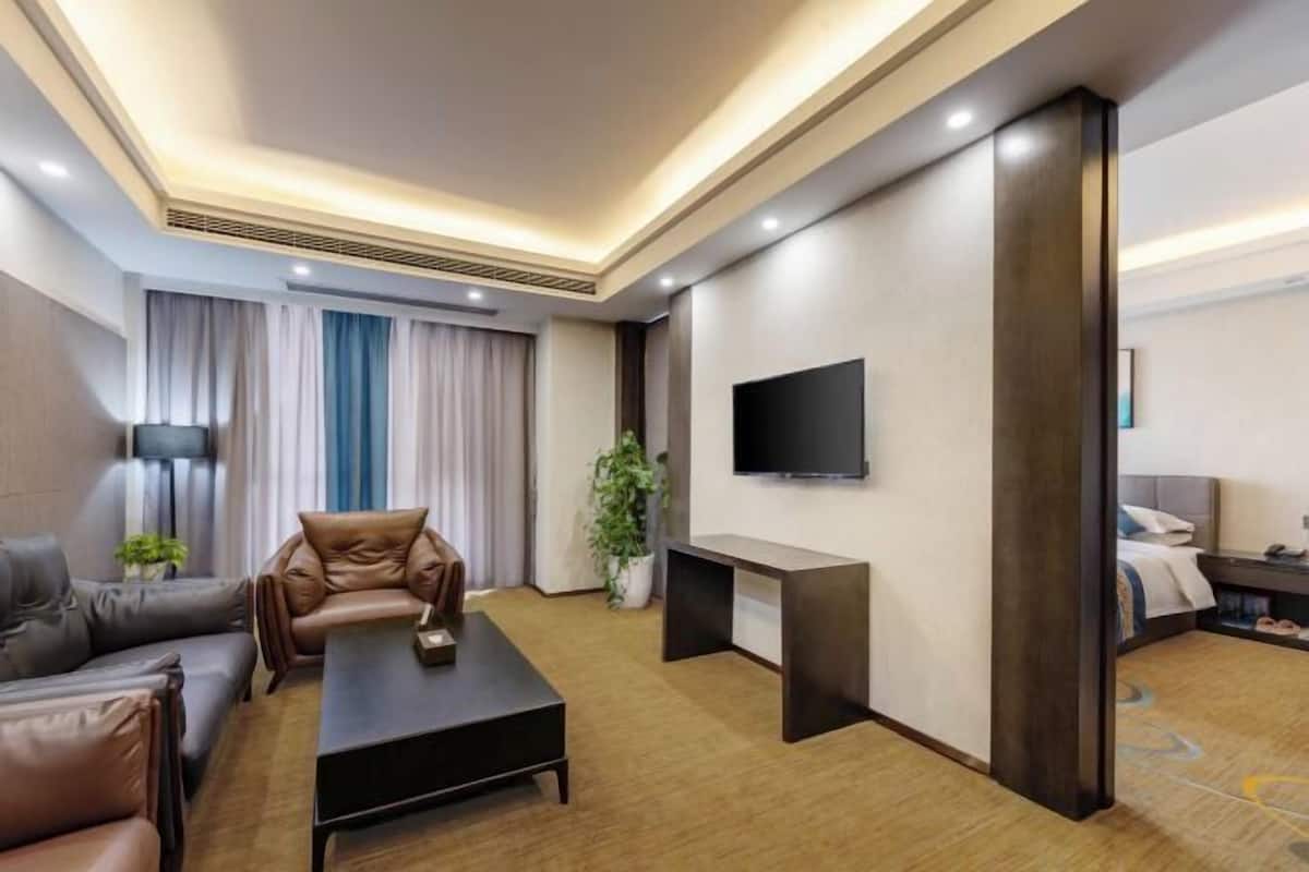 Ein modernes Hotelzimmer mit Sofa, Couchtisch, Fernseher und Schreibtisch.