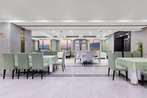 A restaurant with multiple tables and chairs, a view of the cityscape, and a modern interior design. - Ramada by Wyndham Zhangjiajie (Zhangjiajie)